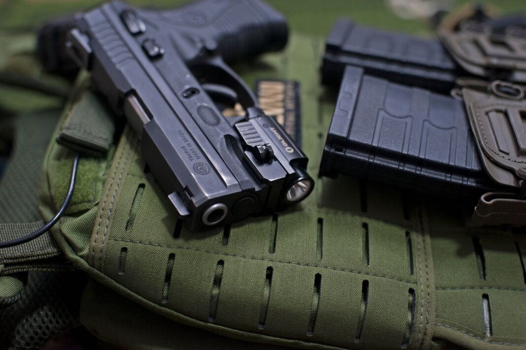 Handgun placed on military gear with tactical accessories, emphasizing modern defense tools.